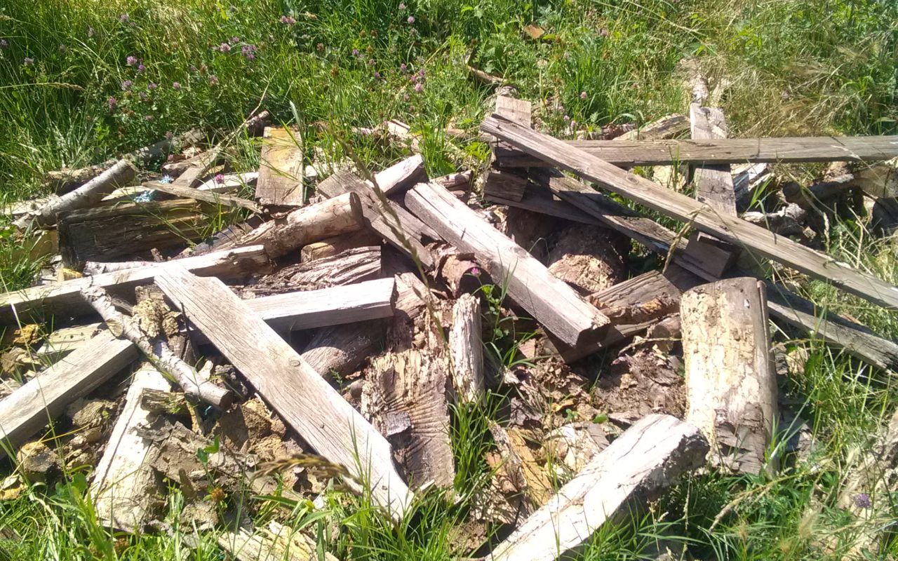 Dépôt sauvage de bois devant une barrière d'accès à la digue